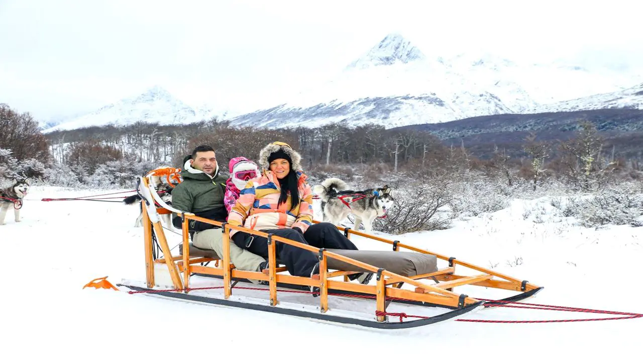 Turistas con indumentaria de tres capas y calzado impermeable por senderos nevados del Fin del Mundo.