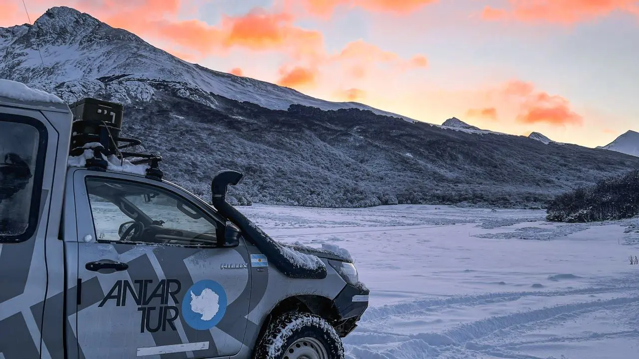Vehículo todoterreno 4x4 cruzando un camino de nieve profunda y barro rodeado de bosques hacia el Lago Fagnano en Ushuaia.